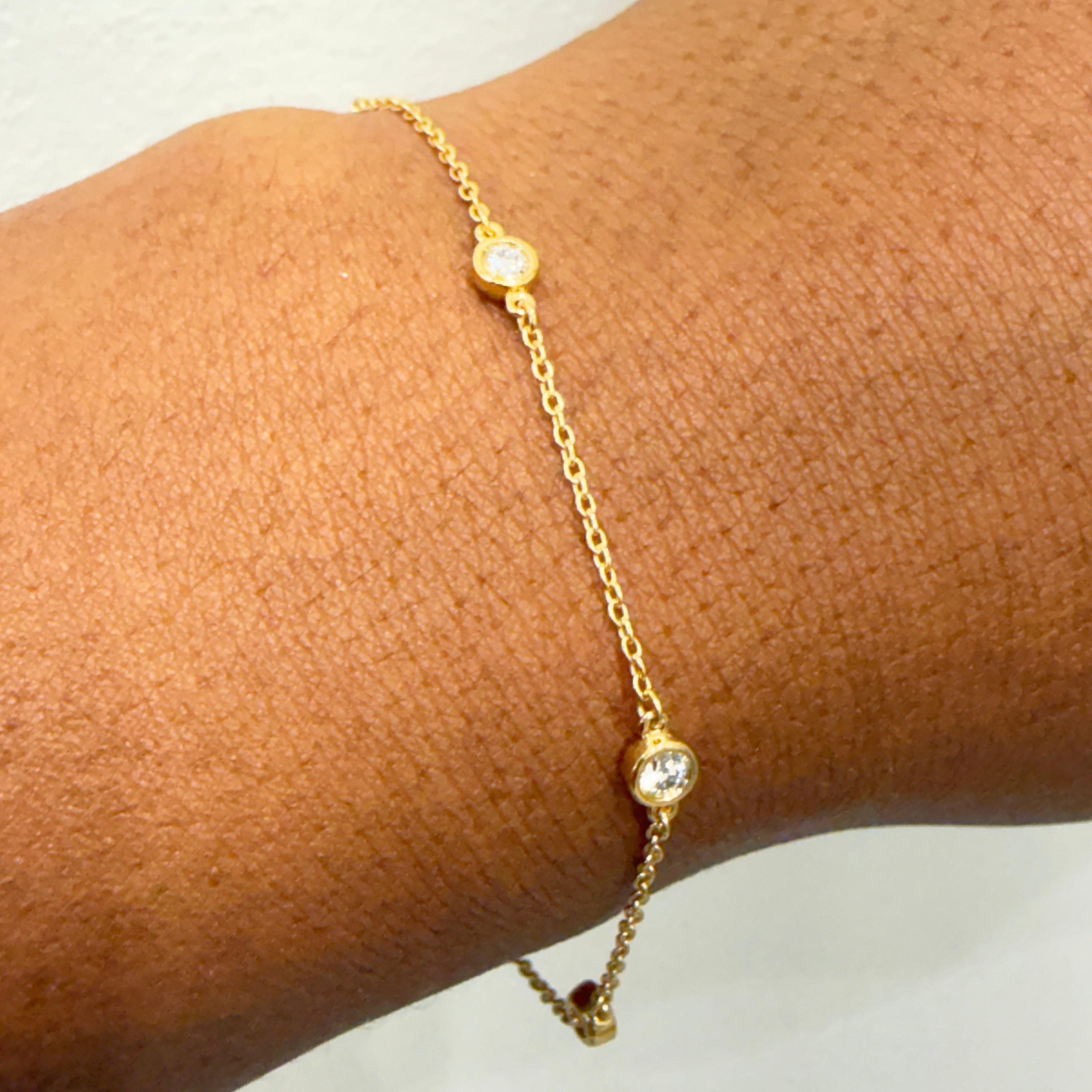 Gold anklet with small round beads on a person's ankle against a neutral background
