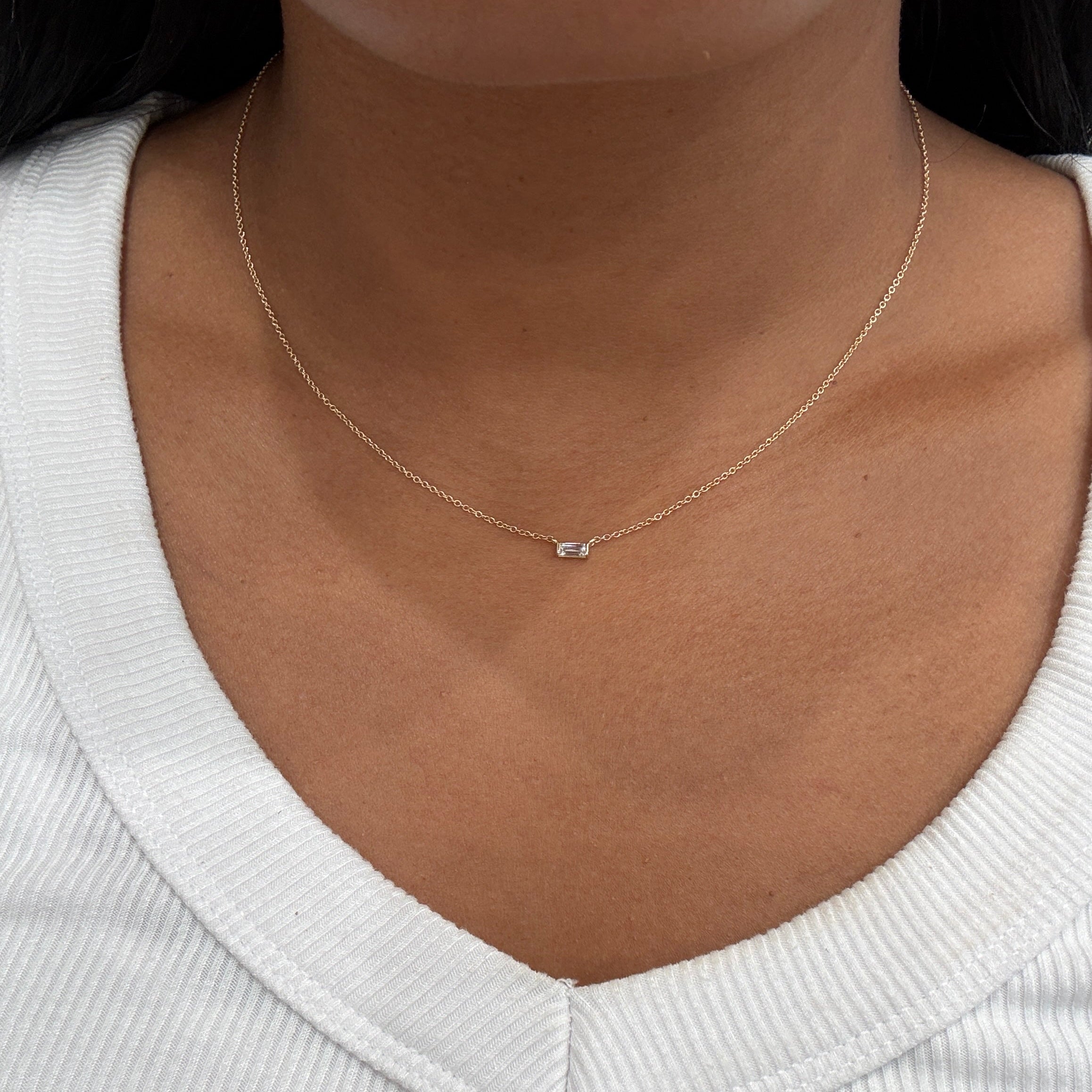 Close-up of a necklace on a person wearing a white sweater.